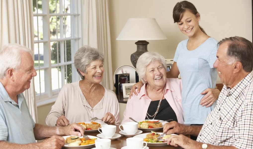 a group of seniors with a caregiver smiling